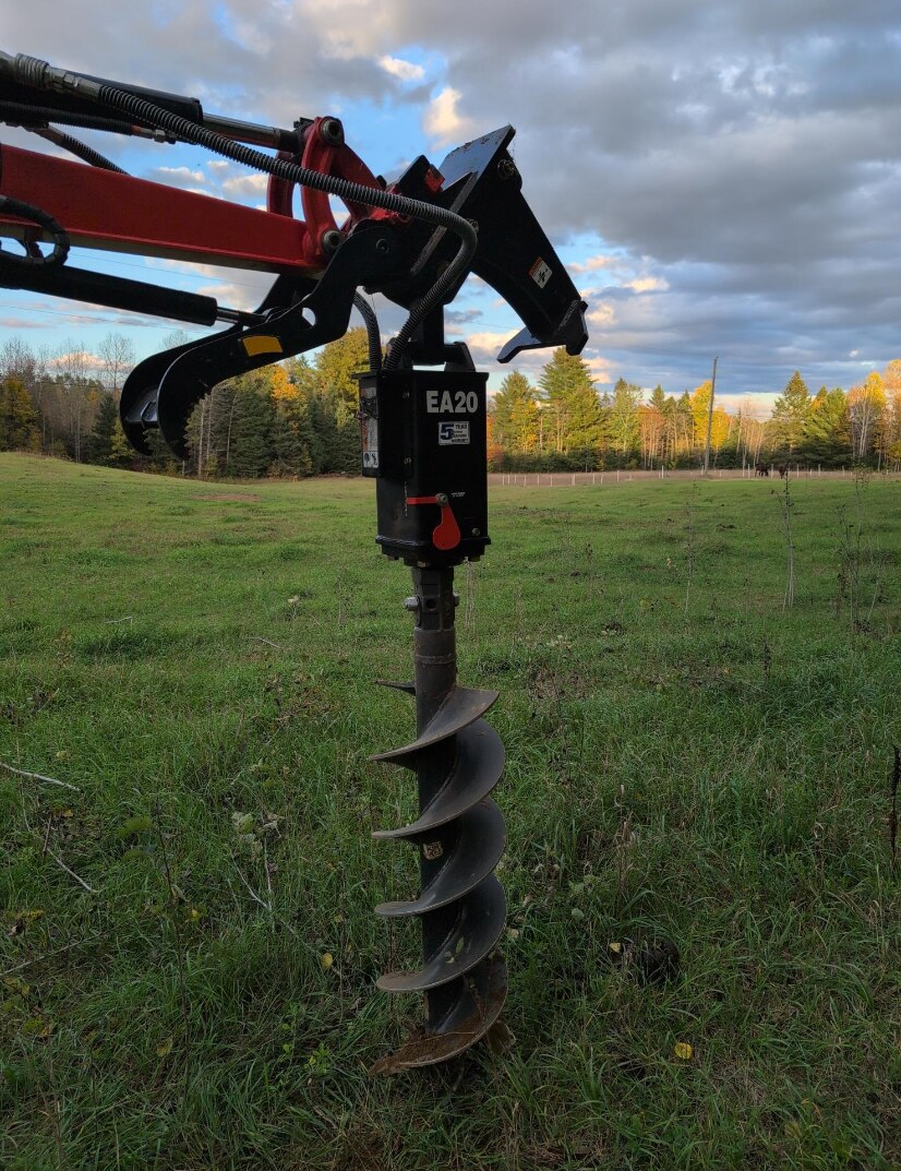 Close-up of the excavator's auger attachment for post installation